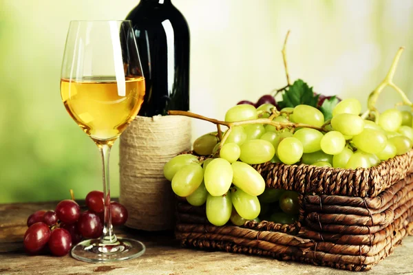 Uva blanca en cesta con botella de vino — Foto de Stock