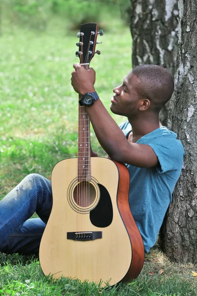 adam parkta oturup gitar ile