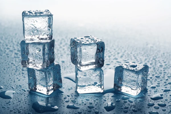 Тающие кубики льда, раскладывающиеся как лестницы с каплями вокруг, закрываются — стоковое фото