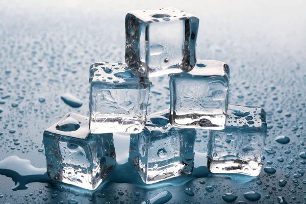 Melting ice cubes putted as pyramid with drops around, close up — Stock Photo, Image