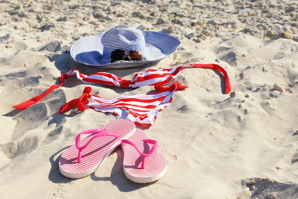 Flip flops, swimsuit and hat on beach sand closeup — Stock Photo, Image