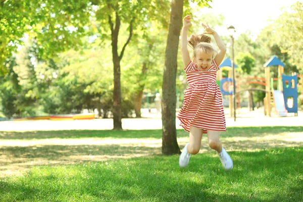 Gelukkig meisje spelen in park in de buurt van de speelplaats — Stockfoto