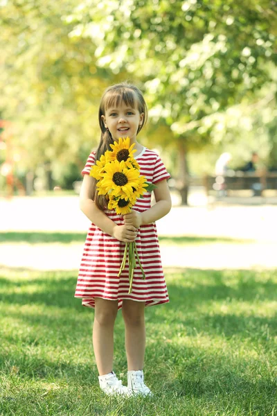 Petite fille avec des tournesols dans le parc — Photo