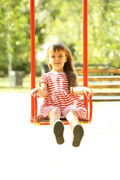 Маленька дівчинка на гойдалках у парку — стокове фото