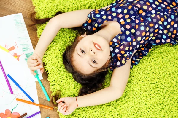 Χαριτωμένο μικρό κορίτσι που κάθεται στο πάτωμα και σχεδιάζοντας εικόνα, σε σπίτι εσωτερικό φόντο — Φωτογραφία Αρχείου