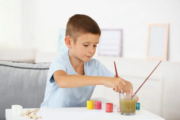 Schattige kleine jongen schilderij beeld op huis interieur achtergrond — Stockfoto