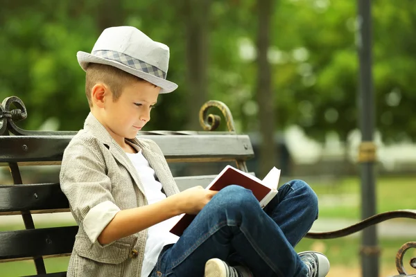 公園のベンチで本を読む少年 — ストック写真