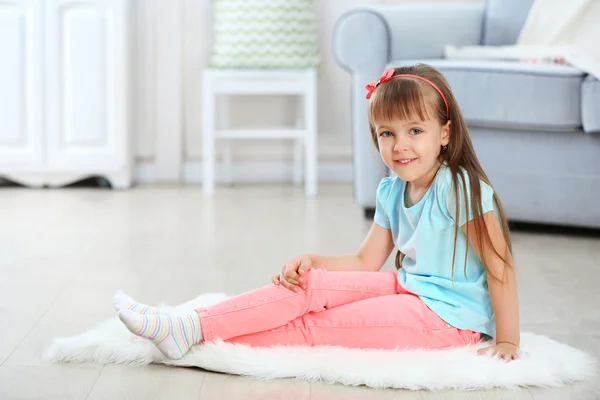 Kleines süßes Mädchen sitzt auf Teppich — Stockfoto