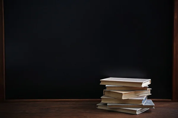 Bücher auf dem Tisch auf Tafel-Hintergrund — Stockfoto