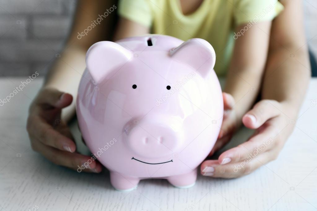 Little girl with her mum and pig  moneybox