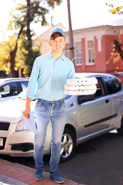 Entrega de pizza menino segurando caixas com pizza perto de carro — Fotografia de Stock