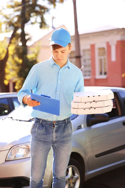 Entrega de pizza menino segurando caixas com pizza perto de carro — Fotografia de Stock