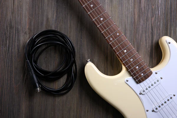 Kytara s kabelem na dřevěné pozadí — Stock fotografie