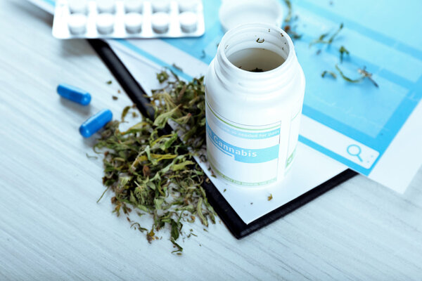 Бутылка сухой медицинской марихуаны и таблетки с планшетом
