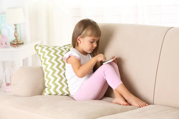 Menina com telefone inteligente sentado no sofá — Fotografia de Stock