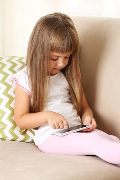 Menina com telefone inteligente sentado no sofá — Fotografia de Stock