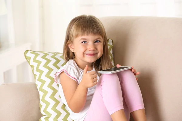 Menina com telefone inteligente sentado no sofá — Fotografia de Stock