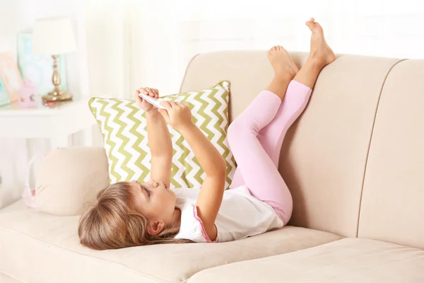 Mädchen mit Smartphone auf Sofa liegend — Stockfoto