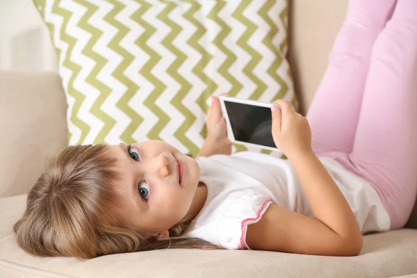 Menina com telefone inteligente deitado no sofá — Fotografia de Stock