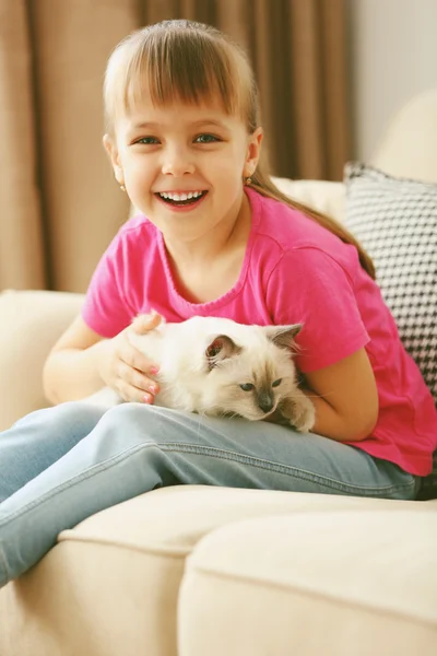 Girl playing with kitten on sofa — Stock Photo, Image