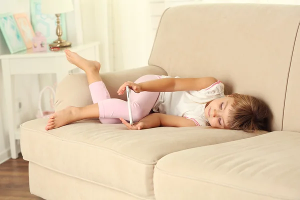 Chica con teléfono inteligente sentado en el sofá — Foto de Stock