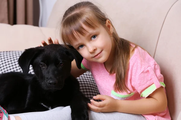 Ragazza con cucciolo sul divano — Foto Stock