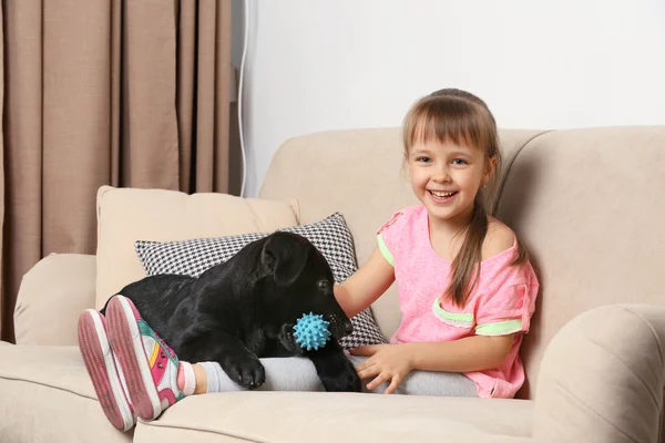 Girl with puppy on sofa Royalty Free Stock Images