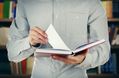 Erkek açık kitap kitap rafı arka planda tutan eller