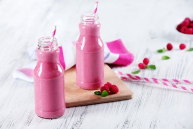 Ahşap masa üzerinde çilek ile Ahududu milkshake şişe yakın çekim