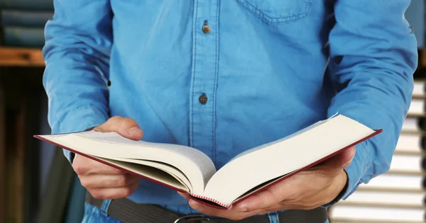 Férfi kezében tartja nyitott könyv a könyvespolcok háttér — Stock Fotó