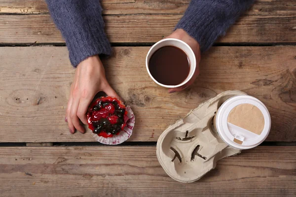 Жіночі руки тримають чашку кави та печива на дерев'яному столі крупним планом — стокове фото