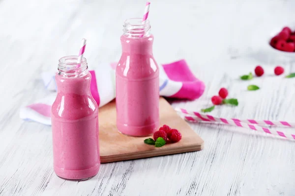 Bottles of raspberry milk shake with berries on wooden table close up — Stock Photo, Image