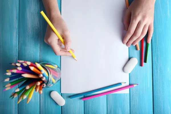 Mão com lápis de cor e folha de papel em branco na mesa de madeira — Fotografia de Stock