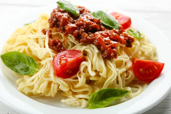 Spaghetti Boloñesa sobre plato blanco, sobre fondo de madera de color — Foto de Stock