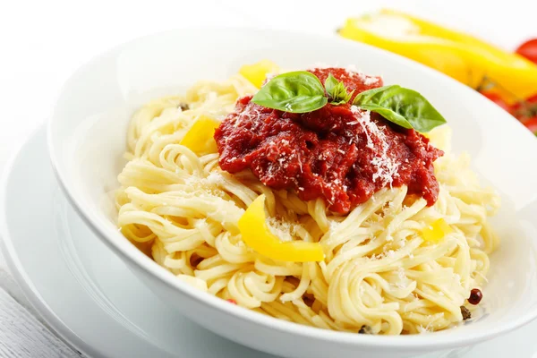 Spaghetti z sosem pomidorowym i serem na białe płytki, drewniane tła kolor — Zdjęcie stockowe