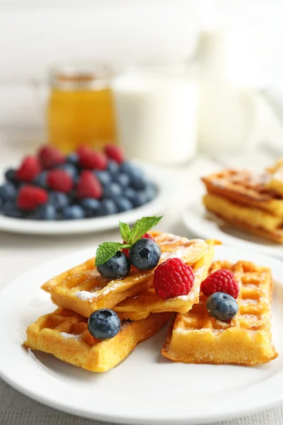 Süße hausgemachte Waffeln mit Waldbeeren und Soße auf Tischhintergrund — Stockfoto