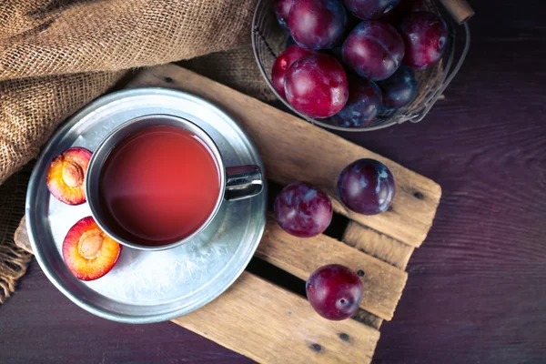 Läckra plommon juice med frukter på bordet på nära håll — Stockfoto