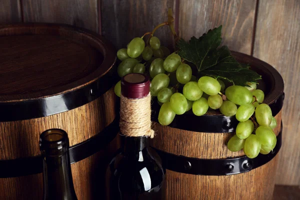 Witte en rode druif met fles wijn op houten achtergrond — Stockfoto