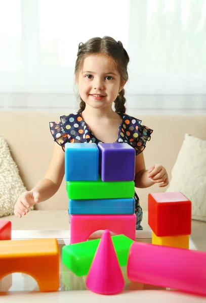 Девочка играет с кубиками на домашнем фоне интерьера — стоковое фото