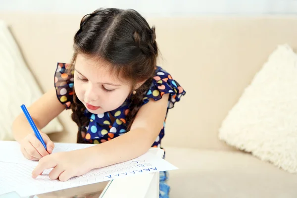 Linda niña haciendo su tarea, primer plano, en el fondo interior del hogar —  Fotos de Stock