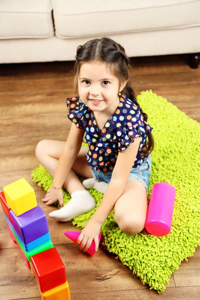 Девочка играет с кубиками на домашнем фоне интерьера — стоковое фото
