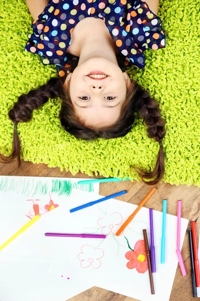 Linda niña sentada en el suelo y dibujo, en el fondo interior del hogar —  Fotos de Stock