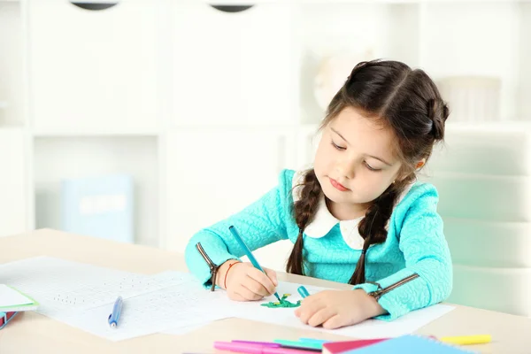 Cute little girl robi pracę domową, zbliżenie, na tle wnętrza domu — Zdjęcie stockowe