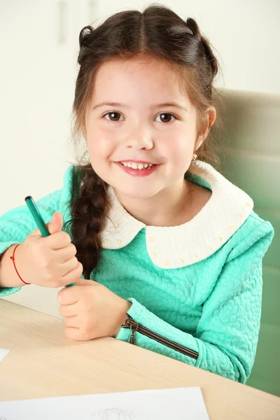 Carina bambina che fa i compiti, primo piano, su sfondo interno di casa — Foto Stock