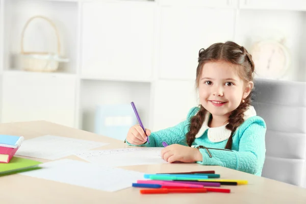 Schattig klein meisje doen haar huiswerk, close-up, op home interieur achtergrond — Stockfoto