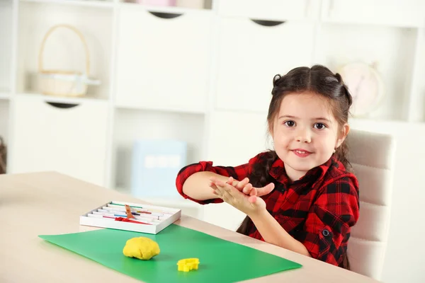 Schattig klein meisje schimmels van plasticine op tafel — Stockfoto