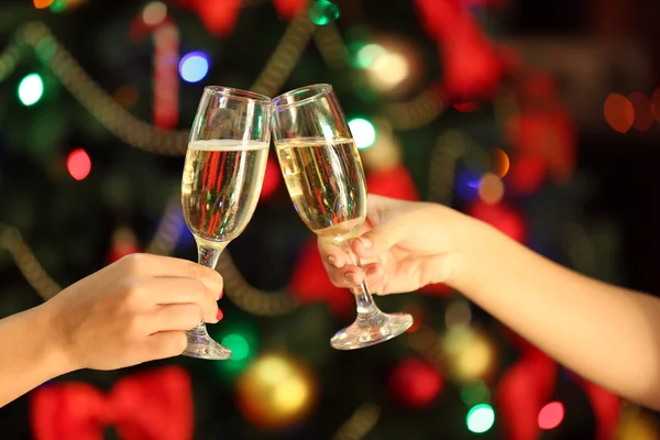 Clinking glasses of champagne in hands on bright lights background — Stock Photo, Image