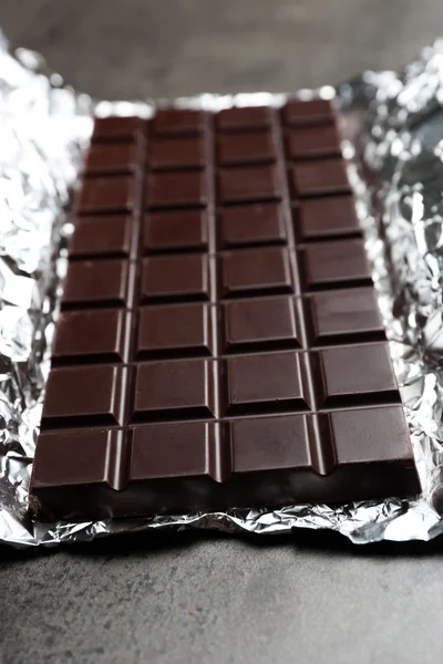 Chocolade bar in folie op grijze achtergrond — Stockfoto