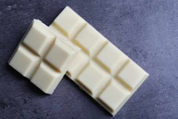 Pedaços de chocolate branco no fundo cinza escuro — Fotografia de Stock