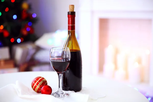 Bottle and glass of wine with Christmas decor against colorful bokeh lights background — Stock Photo, Image